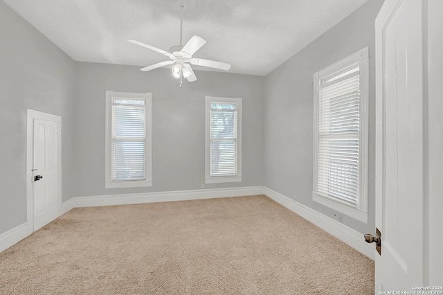 empty room featuring a textured ceiling, light colored carpet, and ceiling fan