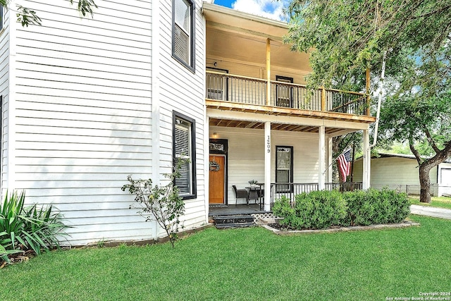 view of front of property featuring a porch, a balcony, and a front lawn