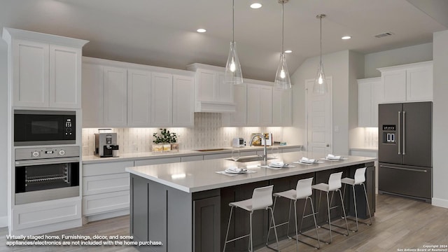 kitchen featuring white cabinetry, an island with sink, black appliances, and light wood-type flooring