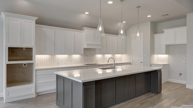 kitchen featuring white cabinetry, a center island with sink, light wood-type flooring, and sink