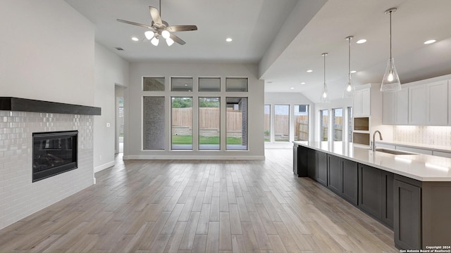 kitchen with ceiling fan, sink, a spacious island, light hardwood / wood-style floors, and white cabinets