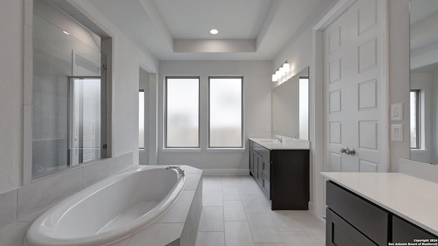 bathroom with vanity, separate shower and tub, a wealth of natural light, and a tray ceiling