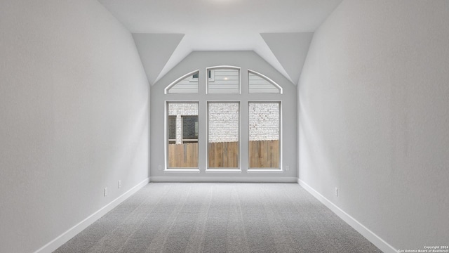 empty room featuring carpet flooring and vaulted ceiling