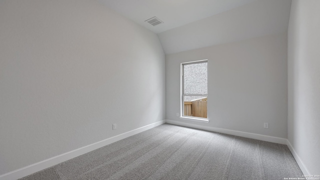 carpeted empty room with vaulted ceiling