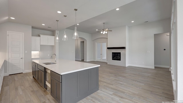 kitchen with ceiling fan, sink, a center island with sink, light hardwood / wood-style flooring, and white cabinetry