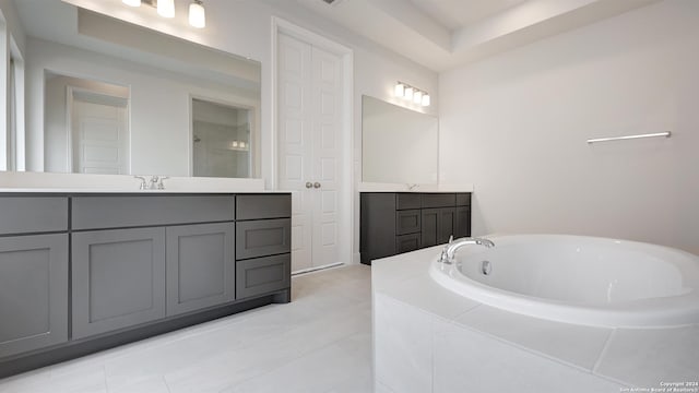 bathroom featuring tile patterned floors, tiled tub, and vanity