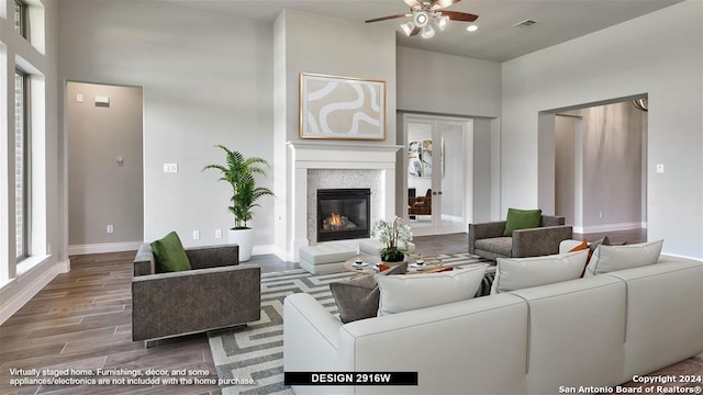 living room with ceiling fan, wood-type flooring, and a high ceiling