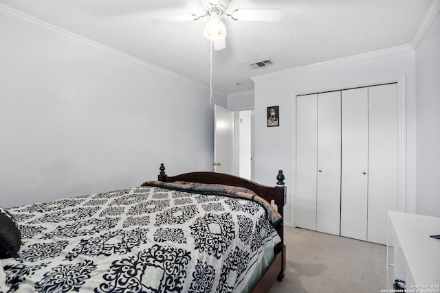 carpeted bedroom featuring a textured ceiling, a closet, ceiling fan, and crown molding