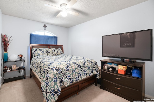 carpeted bedroom featuring ceiling fan and a textured ceiling