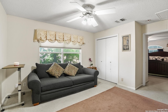 carpeted living room featuring a textured ceiling and ceiling fan