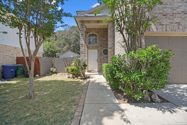 view of exterior entry featuring a yard and a garage