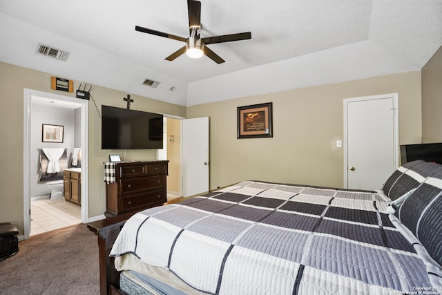 bedroom featuring a textured ceiling, light colored carpet, ensuite bath, and ceiling fan