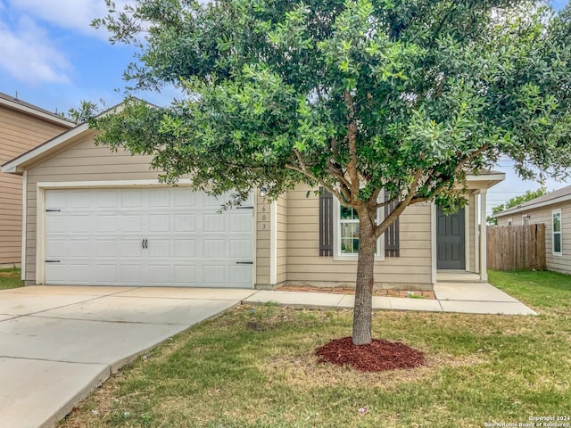 view of property hidden behind natural elements featuring a garage and a front yard