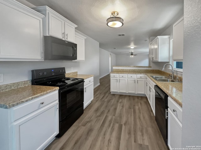 kitchen with light wood-type flooring, ceiling fan, sink, black appliances, and white cabinetry