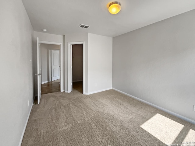 unfurnished bedroom featuring carpet flooring, a spacious closet, and a closet