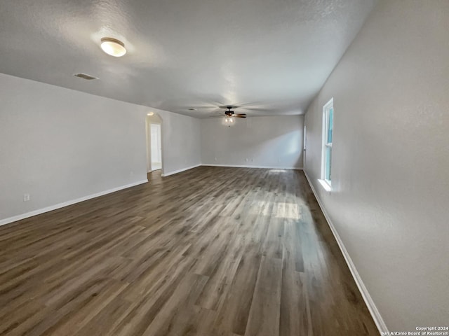 unfurnished living room featuring ceiling fan and dark wood-type flooring