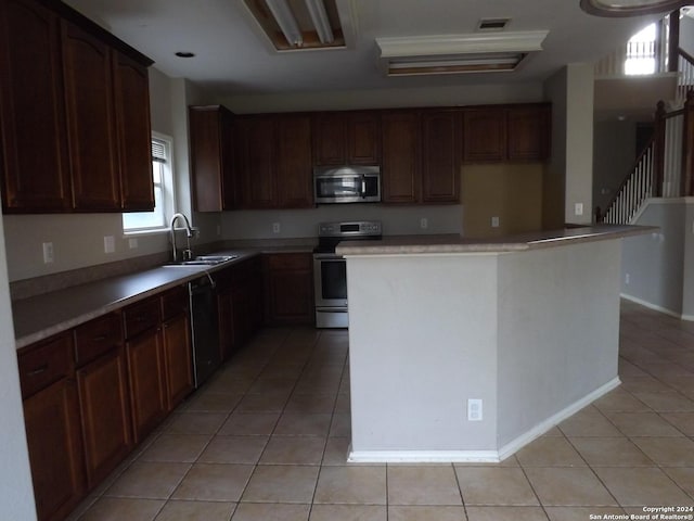 kitchen with light tile patterned flooring, stainless steel appliances, a kitchen island, and sink