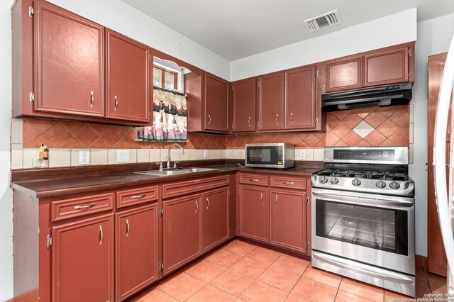 kitchen with sink, backsplash, light tile floors, and stainless steel appliances