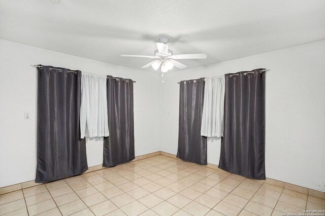 empty room with ceiling fan and light tile floors