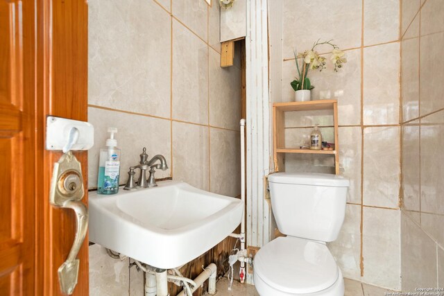 bathroom featuring tile walls, sink, and toilet