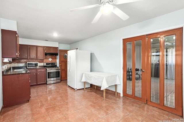 kitchen featuring stainless steel appliances, dark countertops, backsplash, a sink, and under cabinet range hood