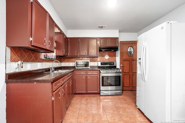 kitchen featuring under cabinet range hood, a sink, visible vents, white fridge with ice dispenser, and gas range