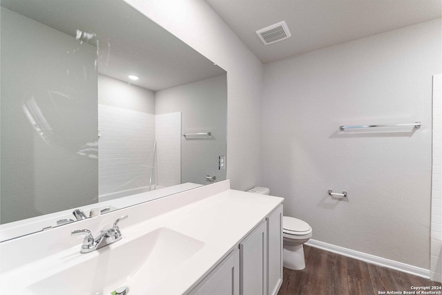 bathroom featuring hardwood / wood-style floors, vanity, toilet, and a shower