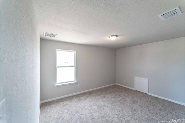 unfurnished room with carpet and a textured ceiling