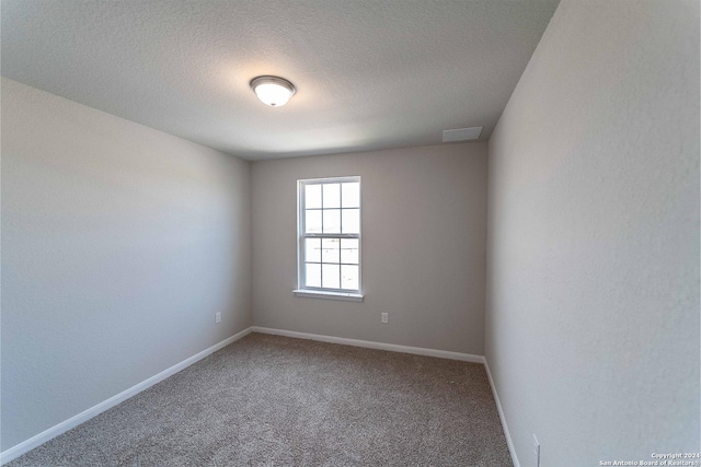 carpeted empty room featuring a textured ceiling