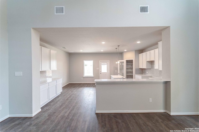 kitchen with white cabinets, dark hardwood / wood-style floors, decorative backsplash, and kitchen peninsula