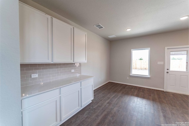 kitchen featuring decorative backsplash, light stone counters, dark hardwood / wood-style flooring, and white cabinets