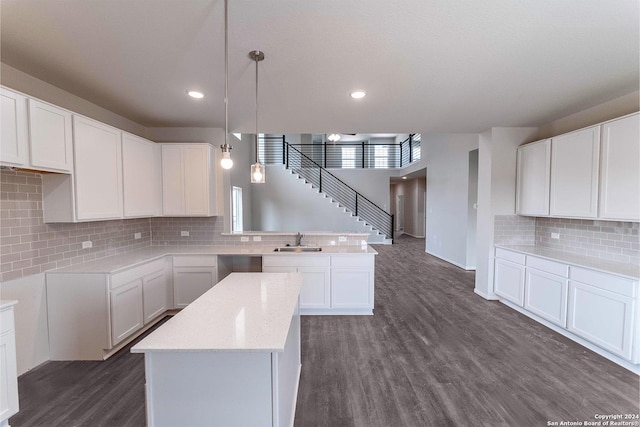 kitchen featuring dark hardwood / wood-style flooring, decorative light fixtures, white cabinetry, and sink