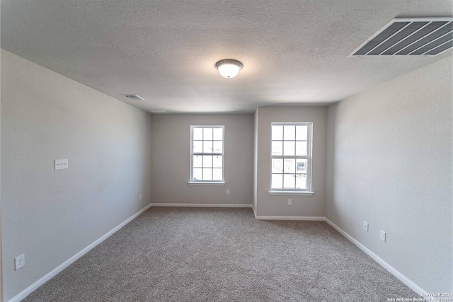 carpeted spare room featuring a textured ceiling