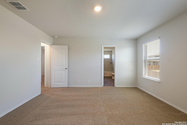 unfurnished bedroom with ensuite bathroom and light colored carpet