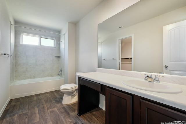 full bathroom with vanity, wood-type flooring, tiled shower / bath combo, and toilet