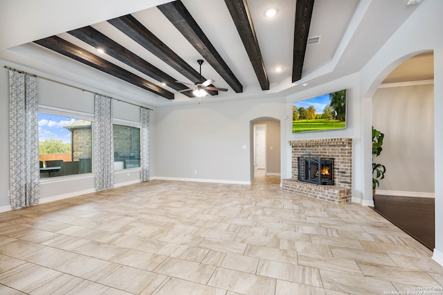 unfurnished living room featuring ornamental molding, a brick fireplace, beam ceiling, ceiling fan, and light tile floors