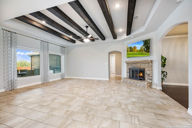 unfurnished living room with a fireplace, beamed ceiling, and ceiling fan