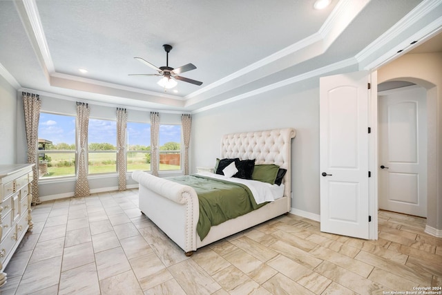 tiled bedroom featuring ceiling fan, a raised ceiling, and crown molding