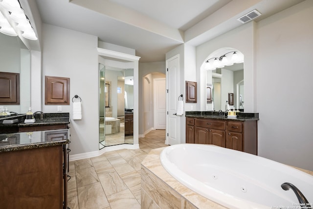 bathroom featuring a relaxing tiled bath, dual bowl vanity, and tile flooring