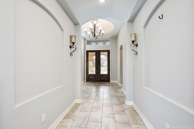 entrance foyer featuring a notable chandelier, french doors, a textured ceiling, and light tile floors