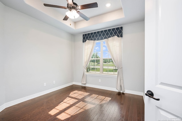 empty room featuring ceiling fan, a raised ceiling, and dark hardwood / wood-style flooring