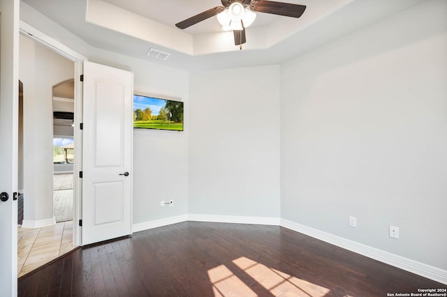 unfurnished room with hardwood / wood-style flooring, ceiling fan, and a tray ceiling