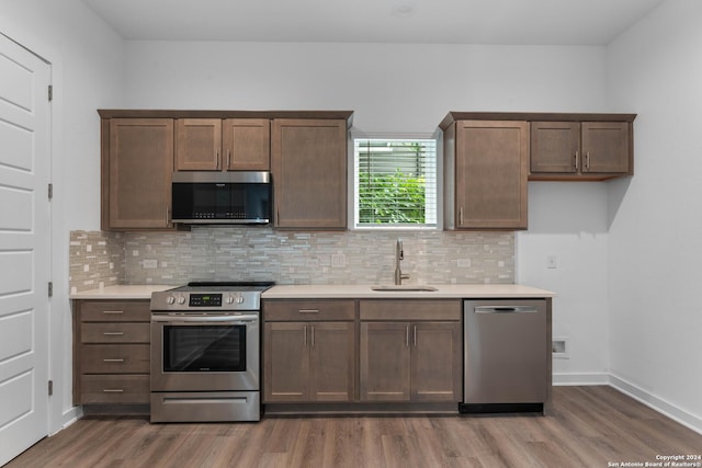 kitchen with sink, backsplash, dark hardwood / wood-style flooring, and stainless steel appliances