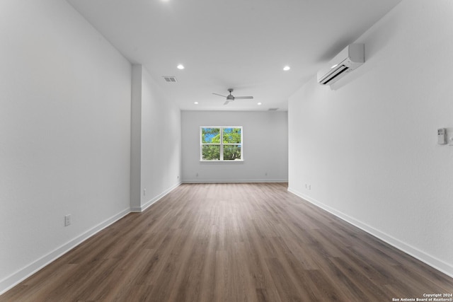 unfurnished room with a wall mounted AC, ceiling fan, and dark hardwood / wood-style flooring