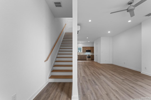 staircase with hardwood / wood-style flooring and ceiling fan