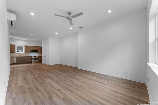 unfurnished living room featuring light hardwood / wood-style floors, a wall mounted AC, and ceiling fan