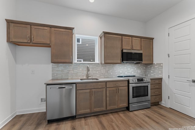 kitchen with decorative backsplash, sink, hardwood / wood-style flooring, and stainless steel appliances