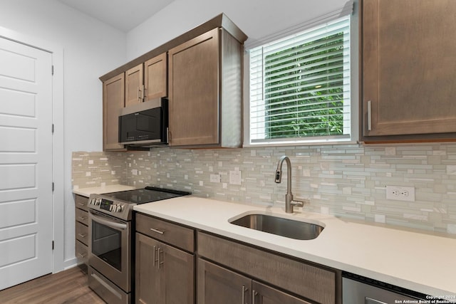 kitchen with sink, dark hardwood / wood-style flooring, stainless steel appliances, and tasteful backsplash