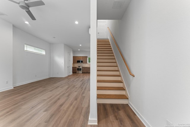 staircase featuring ceiling fan and hardwood / wood-style floors