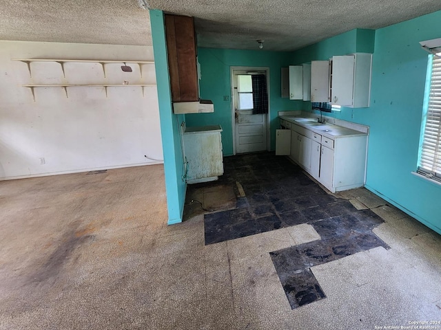 kitchen with white cabinets, a textured ceiling, and sink